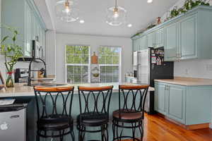 Kitchen featuring stainless steel appliances, light countertops, a peninsula, a kitchen bar, and light wood-style flooring
