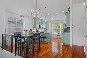Dining space featuring an inviting chandelier, baseboards, wood finished floors, and recessed lighting