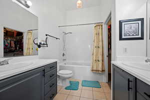 Bathroom featuring toilet, shower / tub combo, tile patterned flooring, vanity, and a walk in closet