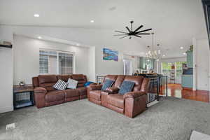 Carpeted living area with recessed lighting, vaulted ceiling, baseboards, and ceiling fan with notable chandelier