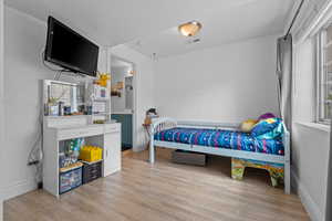 Bedroom featuring light wood-type flooring, baseboards, and visible vents