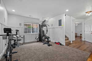 Exercise room with a wainscoted wall, wood finished floors, visible vents, a decorative wall, and a textured ceiling
