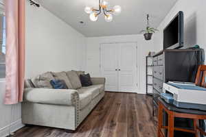 Living room featuring visible vents, dark wood-style flooring, baseboards, a textured ceiling, and a notable chandelier