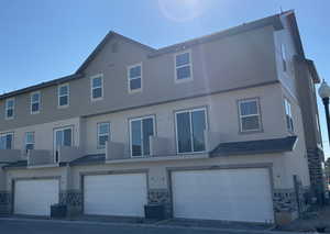 Back of property with central air condition unit, an attached garage, and stucco siding