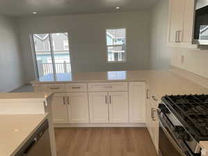 Kitchen with white cabinets, stainless steel appliances, light countertops, and a peninsula