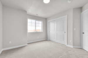 Unfurnished bedroom featuring visible vents, a closet, baseboards, a textured ceiling, and carpet flooring