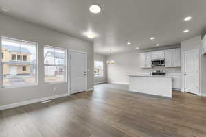 Kitchen with a chandelier, baseboards, appliances with stainless steel finishes, dark wood-style floors, and recessed lighting