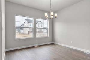 Spare room featuring visible vents, baseboards, and a notable chandelier