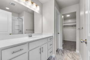 Full bathroom with marble finish floor, visible vents, vanity, baseboards, and walk in shower