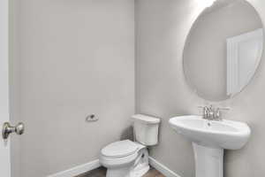 Bathroom with baseboards, toilet, and wood finished floors