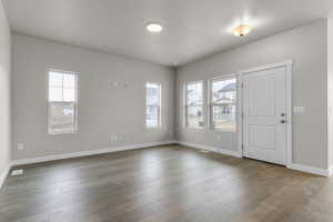 Spare room with baseboards and dark wood-type flooring
