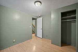 Unfurnished bedroom with baseboards, wood finished floors, and a textured ceiling
