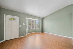 Foyer entrance with lofted ceiling, visible vents, light wood finished floors, and baseboards