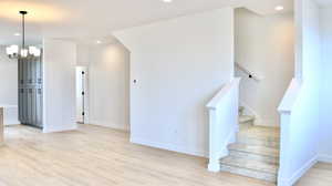 Stairway featuring baseboards, a notable chandelier, wood finished floors, and recessed lighting