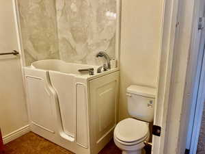 Full bath with toilet, a textured wall, and tile patterned flooring