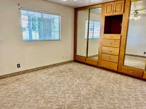 Unfurnished bedroom with light carpet and multiple windows