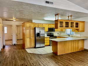 Kitchen featuring light wood-type flooring, a peninsula, visible vents, and appliances with stainless steel finishes