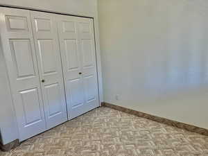 Unfurnished bedroom with light colored carpet and a closet