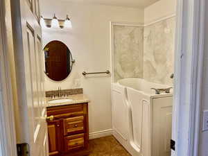Bathroom with tile patterned flooring, vanity, washer / dryer, a bath, and baseboards