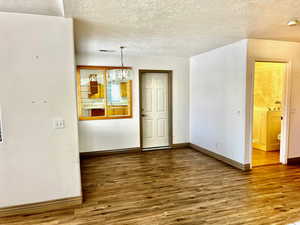 Unfurnished dining area with wood finished floors, a textured ceiling, baseboards, and visible vents