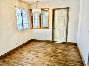Unfurnished dining area featuring wood finished floors, visible vents, baseboards, and a notable chandelier