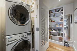 Laundry room with wood finished floors, stacked washer and dryer