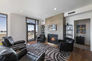 Living room featuring wood finished floors, recessed lighting, and a stone fireplace