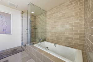Full bath with a bath, tile patterned flooring, and a shower stall