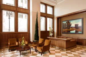 Sitting room featuring plenty of natural light, a towering ceiling, and light floors
