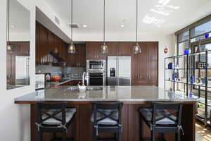 Kitchen featuring a sink, appliances with stainless steel finishes, backsplash, and under cabinet range hood
