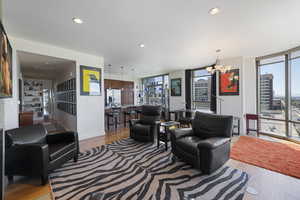 Living area with expansive windows, a notable chandelier, light wood-style floors, and recessed lighting