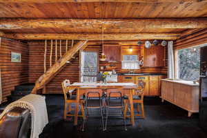 Dining room featuring a wealth of natural light, log walls, and beam ceiling