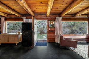 Living area with plenty of natural light, log walls, and beam ceiling