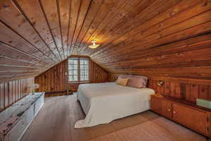 Bedroom featuring wooden ceiling, lofted ceiling, wood walls, and wood-type flooring