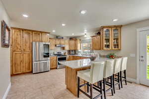 Kitchen featuring under cabinet range hood, stainless steel appliances, a breakfast bar, a peninsula, and glass insert cabinets