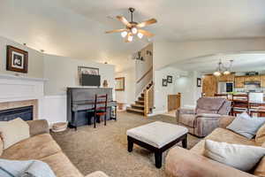 Living area featuring arched walkways, lofted ceiling, ceiling fan, and light carpet