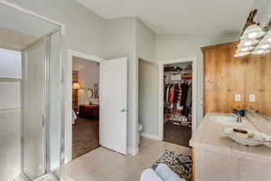 Bathroom featuring vaulted ceiling, tile patterned flooring, a sink, and a stall shower