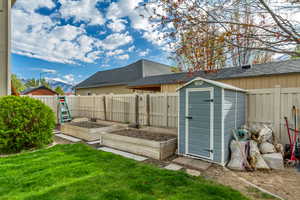 View of shed with a fenced backyard, a garden, and a mountain view
