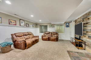 Living area featuring visible vents, built in shelves, ornamental molding, and a decorative wall