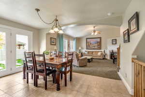 Dining room featuring light carpet, a ceiling fan, arched walkways, and light tile patterned floors