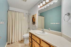 Bathroom with vanity, visible vents, toilet, tile patterned flooring, and shower / bath combo with shower curtain