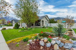 View of front of property featuring a mountain view, fence, a garage, a front yard, and stucco siding