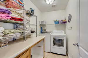 Laundry room featuring light tile patterned floors, visible vents, washer and dryer, and laundry area