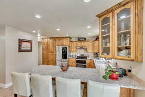 Kitchen featuring recessed lighting, under cabinet range hood, stainless steel appliances, a sink, and a peninsula