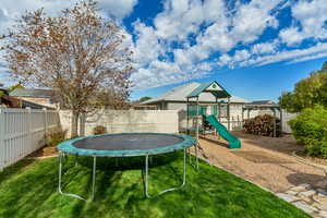 View of play area featuring a yard, a trampoline, and a fenced backyard