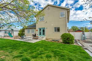 Back of house featuring a playground, a garden, stucco siding, a patio area, and fence private yard