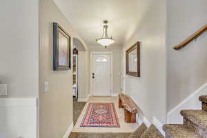 Entrance foyer with baseboards, arched walkways, stairs, and light tile patterned floors