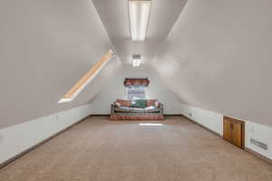 Bonus room featuring lofted ceiling, visible vents, baseboards, and light carpet
