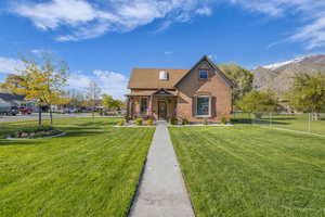 View of front facade with brick siding, a front lawn, fence, and a mountain view