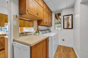 Laundry room with light wood finished floors, laundry area, a sink, a wealth of natural light, and baseboards